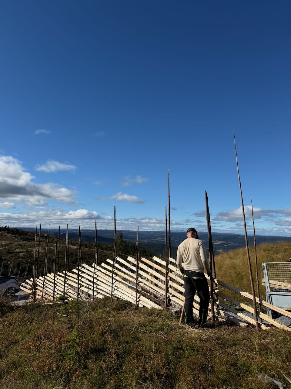 Skigardbygging i fjellterreng — staurpar er satt opp og skiene legges på skrå